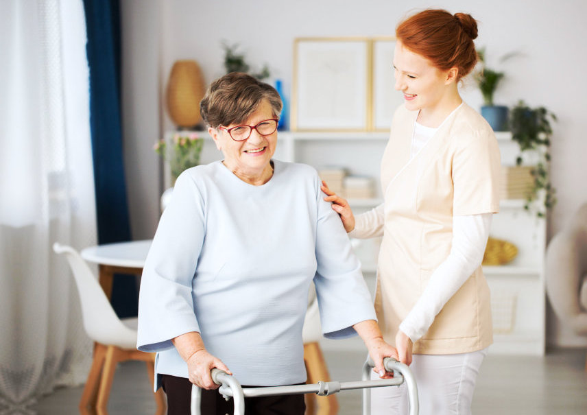 caregiver helping the patient walk while smiling for the camera