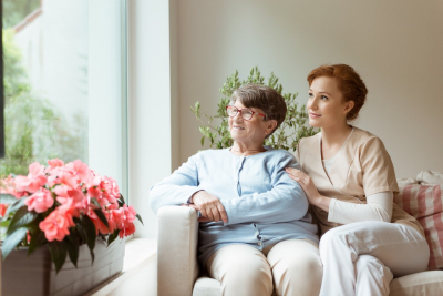 senior and caregiver sitting on couch looking outside