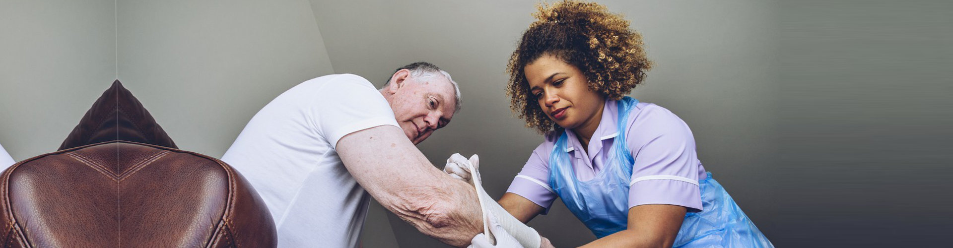 nurse putting bandage on senior man's arm
